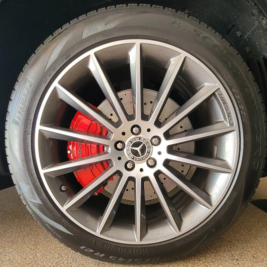 Close-up of a Mercedes Benz GLE wheel with a silver rim and red brake caliper on a concrete floor.