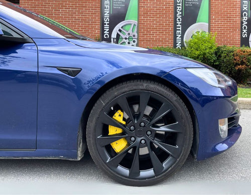 A closeup on a Tesla yellow custom caliper cover made by Leprecon Plus.