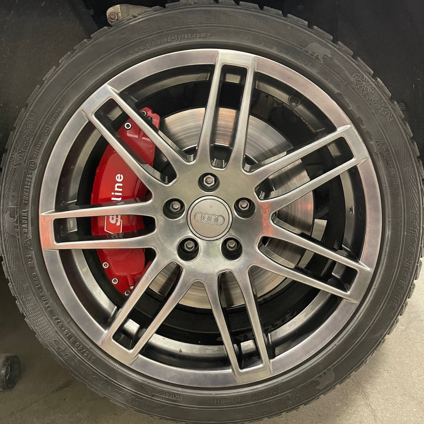 Close-up of a car wheel with a silver rim and red brake caliper.