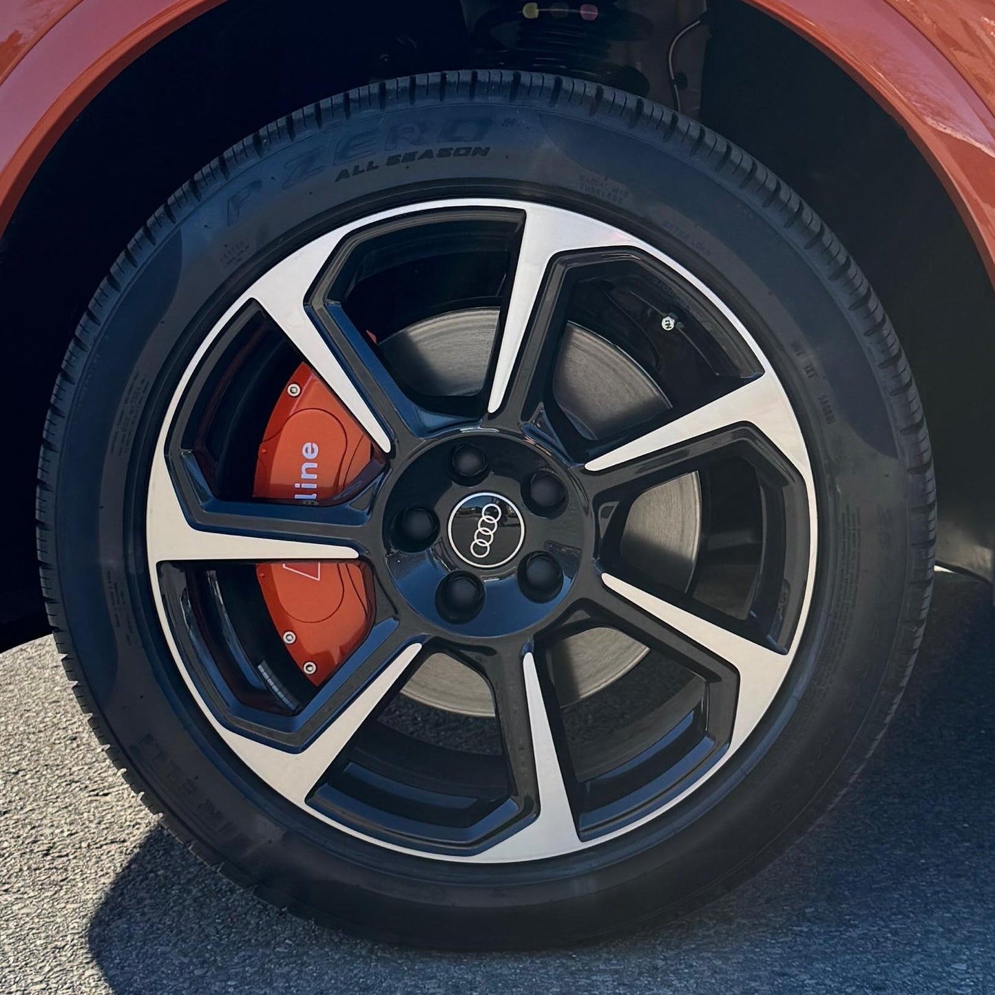 Close-up of a car wheel with Audi Q3 logo on a red vehicle