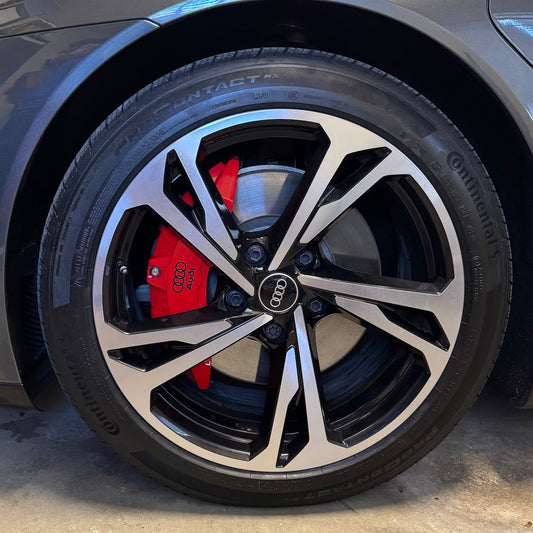 Close-up of a Audi wheel with red brake caliper in a garage setting