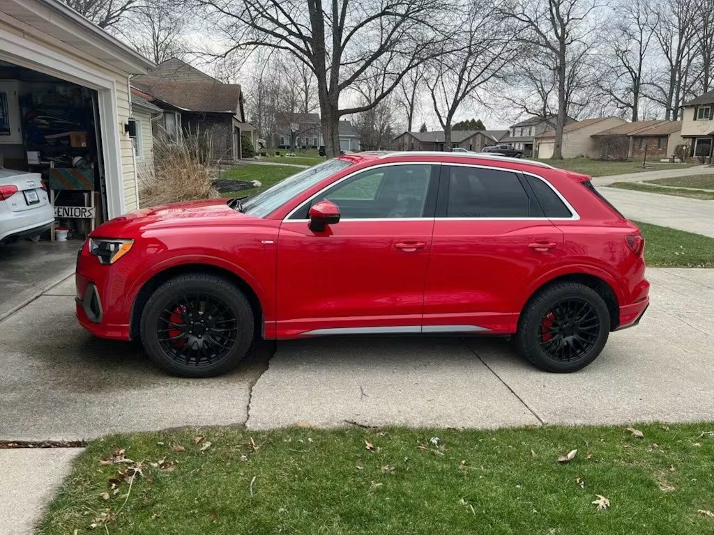 Red SUV Audi Q3 parked on a driveway with a suburban neighborhood in the background